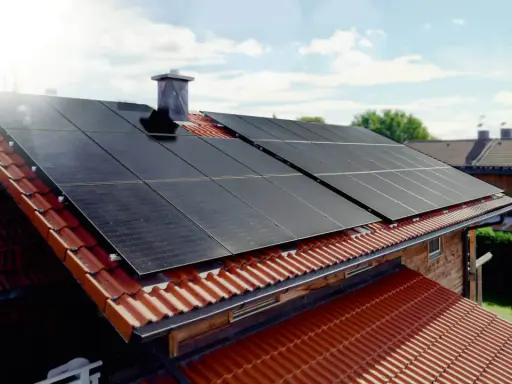 Solceller tillverkning på ett tegeltak. Solen skiner på panelerna som fångar upp energin.
