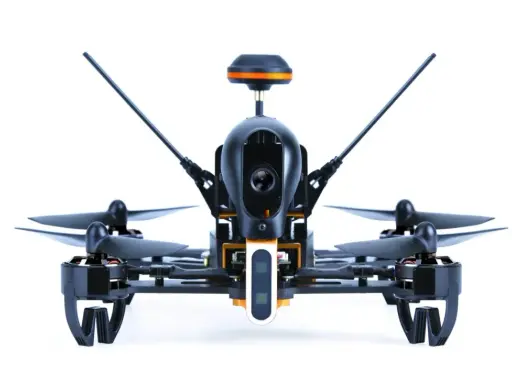 Ich sehe aus der **first person view** auf einen schwarzen Quadrocopter mit orangefarbenen Akzenten. Seine Kamera ist bereit für den Flug.