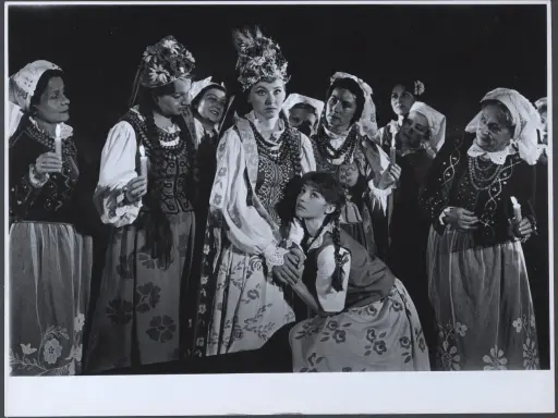 Grupa kobiet w tradycyjnych strojach, z zapalonymi świecami, przygotowuje się do klimina wesele.