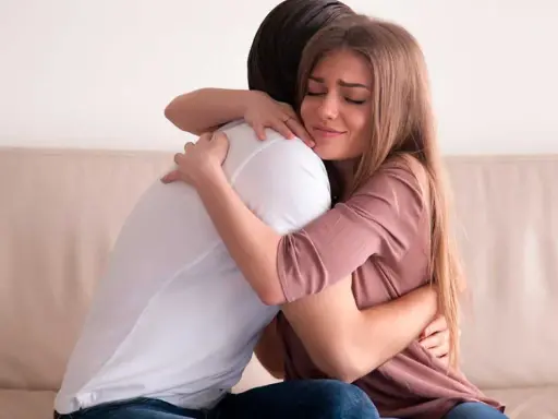 Mujer llorando abraza a hombre. Podría ser un ejemplo de frases de disculpas por no asistir a una boda.