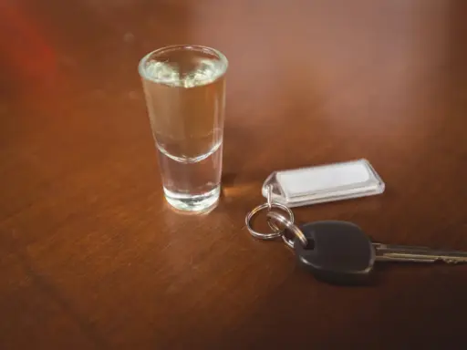 Kieliszek z alkoholem i kluczyki do samochodu. Pamiętaj, że kara za jazdę po pijanemu jest surowa.
