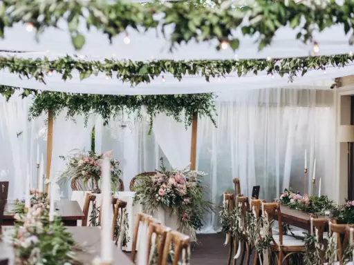 Uroczysty stół weselny w stylu boho, udekorowany kwiatami, zielenią i świecami.