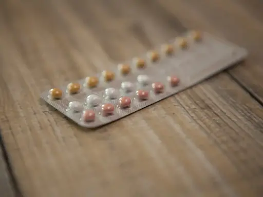 Blister opakowania tabletek antykoncepcyjnych na drewnianym tle. Zastanawiasz się nad tabletki antykoncepcyjne skutki uboczne?