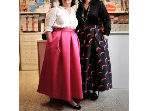 Due donne mostrano diversi tipi di gonne: una rosa a pieghe e una nera con stampa a mezzelune rosa.
