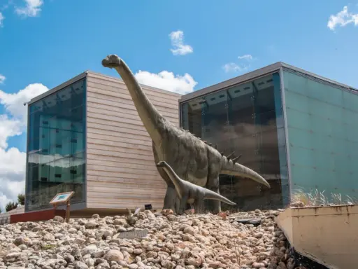 Modelos de dinosaurios frente a edificios modernos. Un plan perfecto para saber qué ver en Cuenca con niños.