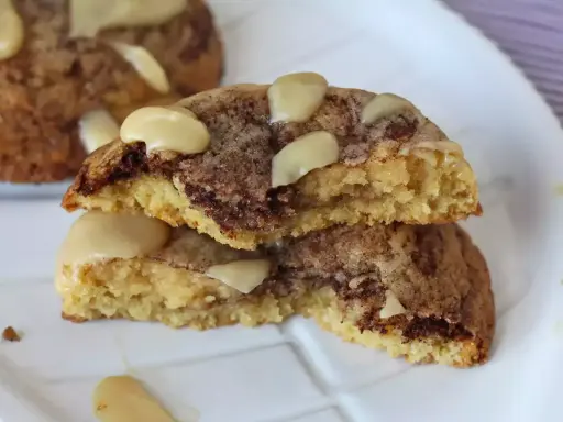 Biscotti alla cannella con gocce di cioccolato e mandorle, uno spezzato mostra l'interno morbido e profumato.