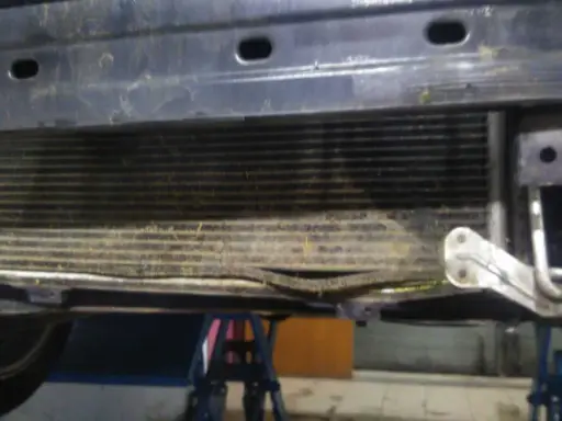 Uszkodzony skraplacz klimatyzacji objawy: zgięte żeberka, widoczne uszkodzenia mechaniczne.