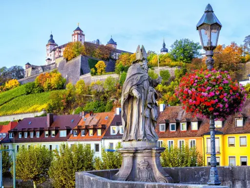 Statua sul ponte di Würzburg, con la fortezza in cima alla collina e i vigneti. Perfetto per un itinerario di 7 giorni sulla Romantische Straße.