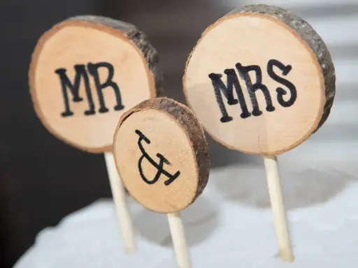Drewniane krążki z napisami MR i MRS, symbolizujące Parę Młodą, ozdabiają tort.