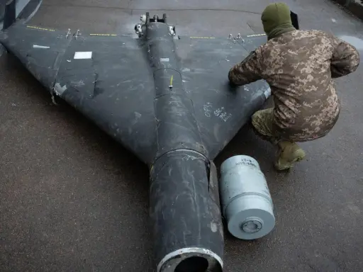Ein Soldat inspiziert eine Drohne in Rumänien. Daneben liegt eine Munitionshülse.