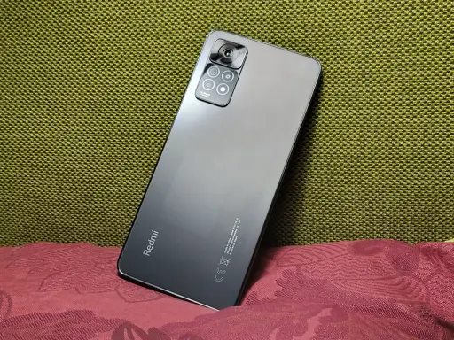 Elegancki, szary Redmi Note 11 Pro 5G Plus z aparatem 108MP na tle zielonej i bordowej tkaniny.
