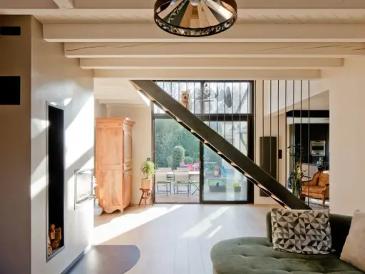 Rénovation d'une maison année 70 : avant, un style désuet ; après, un espace lumineux avec escalier moderne, poêle design et vue sur jardin.