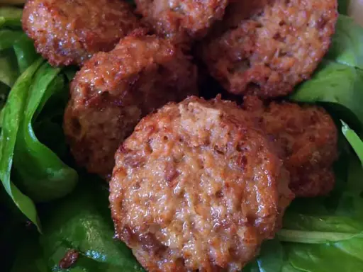 Polpette di lenticchie dorate e croccanti su un letto di spinaci freschi.