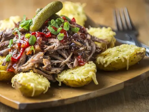 Pulled pork med en härlig sås till, serverad med ugnsbakade potatishalvor gratinerade med ost och en dillkvist.