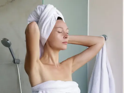 Frau mit Handtuch auf dem Kopf, nach dem Duschen. Sie denkt darüber nach, wie man Reiswasser für die Haarpflege macht.