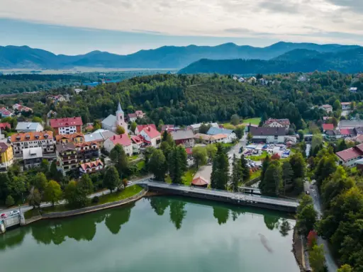 Malownicze miasteczko w Chorwacji, otoczone zielonymi wzgórzami i górami. Jezioro odbija kolorowe dachy domów.
