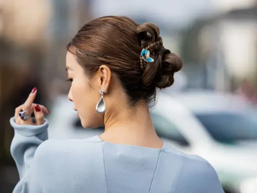 Peinado recogido con trenzas y moños, adornado con un pasador de mariposa. Un look de recogidos sencillos y elegantes.