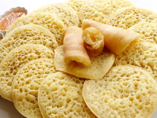 Assiette de crêpes mille trous, garnies de miel et de cacahuètes concassées. Un délice à déguster !