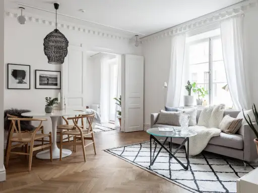 Ljust och luftigt vardagsrum med matbord och inspiration från skandinavisk design. En rund vit matplats med trästolar möter en soffgrupp med mysiga textilier.