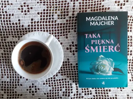 Kawa i książka Magdaleny Majcher "Taka piękna śmierć" na białej serwetce.