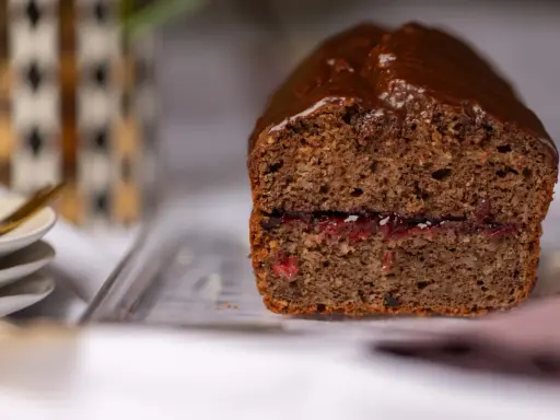 Saftiger buchweizen kuchen mit Schokoladenglasur und einer Füllung aus roter Marmelade.