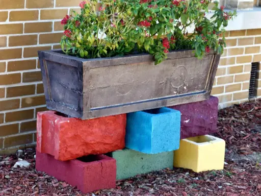 Un bac à fleurs sur des blocs de béton colorés, une idée de **diy jardin** pour rehausser vos plantes.