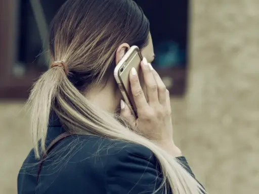 Kobieta rozmawia przez telefon, martwiąc się, czy pracodawca może odmówić urlopu na żądanie.