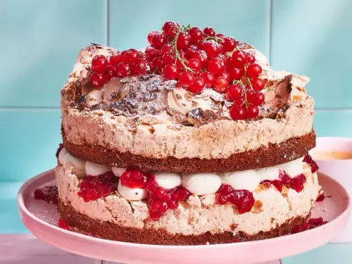 Ein zweistöckiger Johannisbeerkuchen mit Baiser, Sahne und roten Johannisbeeren, bestäubt mit Puderzucker und Mandelsplittern.