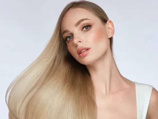 Blonde Frau mit glänzendem Haar, das durch Proteine gestärkt wurde.