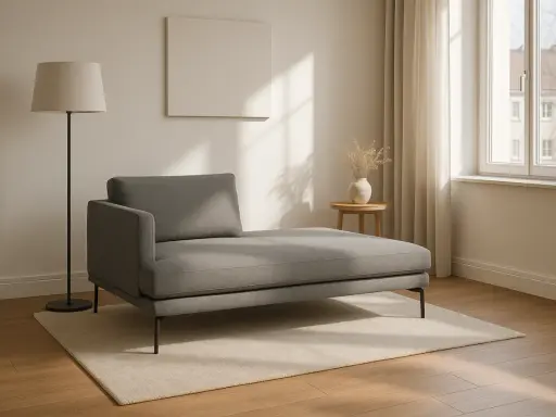 Chaise longue grigia moderna su tappeto chiaro, con lampada da terra e tavolino. Le misure sono perfette per un angolo relax.