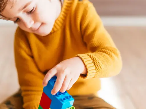 Niño concentrado jugando con bloques de construcción. Un ejemplo de cómo el juego puede ayudar a superar un retraso madurativo y TDAH.