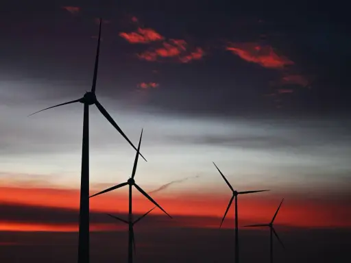 Silhouetten von Windkraftanlagen in den Niederlanden vor einem dramatischen Sonnenuntergang mit roten Wolken.
