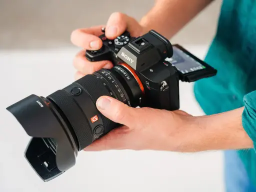 Dłonie trzymają aparat Sony a7r5 z obiektywem 24-70mm.