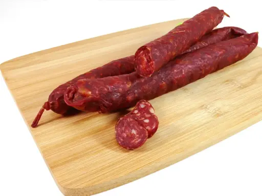 Trzy kawałki pikantnego chorizo na desce. Zastanawiasz się chorizo co to? To aromatyczna, suszona kiełbasa.