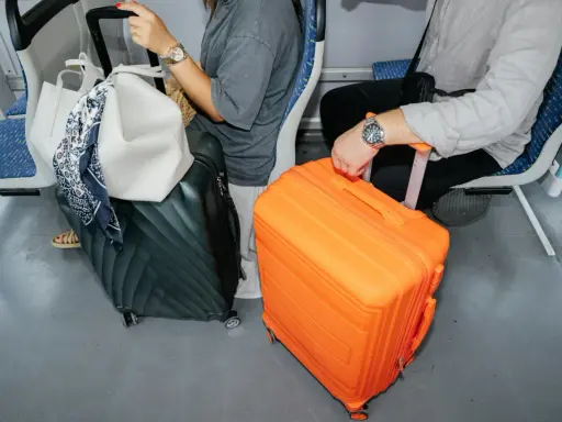 Pomarańczowa walizka i zielona walizka obok siebie, gotowe na podróż. Idealny bagaż podręczny Sky Express.