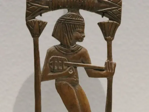 Sculpture en bois d'un musicien égyptien jouant d'un instrument ancien, ornée de motifs floraux.