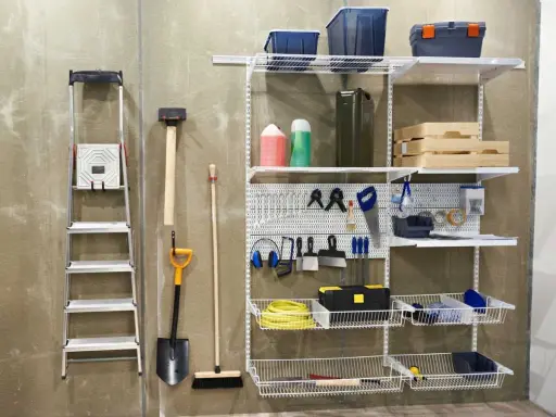 Estanterías y herramientas para saber como ordenar un garaje: escalera, pala, escoba, martillo, caja de herramientas, cubos y más.