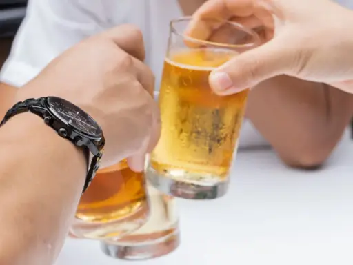 Dwie osoby wznoszą toast piwem. Pytanie: czy chory na raka może pić alkohol?