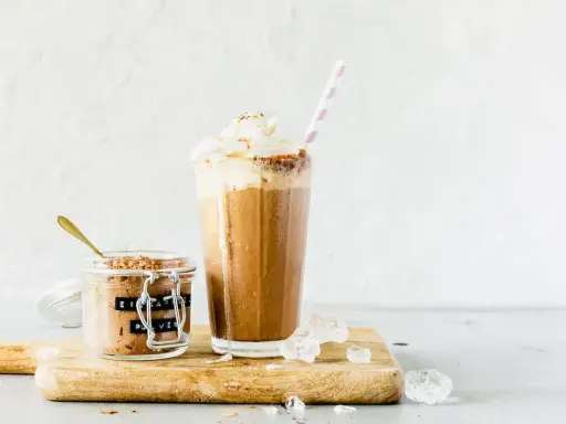 Eiskaffee mit gekochtem Kaffee, zubereitet im Thermomix, gekrönt mit Sahne. Daneben ein Glas mit Eiskaffee-Pulver.
