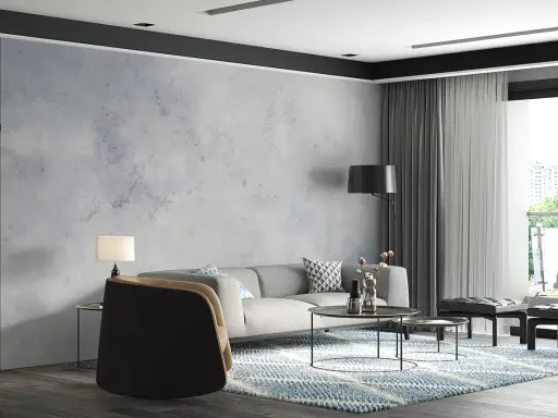 Nowoczesny salon z szarą sofą i fotelem. W tle efektowny **beton na ścianie**, który nadaje wnętrzu industrialnego charakteru.