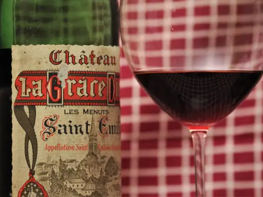 Ein Glas Rotwein neben einer Flasche Château La Grace Dieu, ein Saint-Émilion Grand Cru.