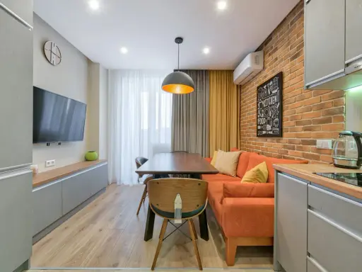 Idée pour aménager salon salle à manger 15m2 : canapé orange, table en bois, mur brique, cuisine moderne.