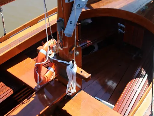 Le bois de bateau verni brille au soleil. Une bouée orange est accrochée, prête pour l'aventure.