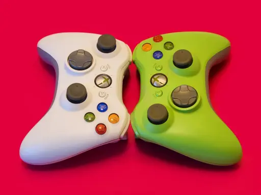 Biały i zielony kontroler Xbox 360 obok siebie. Idealne do gier strategicznych w czasie rzeczywistym, wymagających szybkiego myślenia i precyzji.