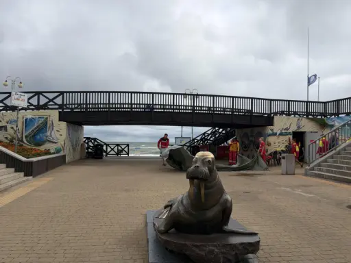 Pomnik foki i most nad plażą w Mielnie. Atrakcje dla turystów, ratownicy przygotowują sprzęt.