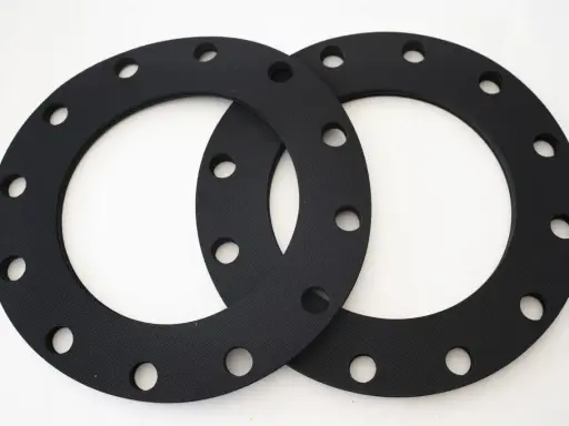 Deux joints sbr noirs, circulaires et percés, prêts à assurer l'étanchéité d'une connexion.