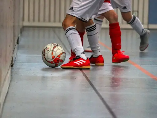 Piłka do futsalu na hali, obok butów zawodników. Tak, w turfy można grać na hali, to właśnie futsal!
