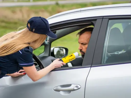 Policjantka mierzy kierowcy alkomatem, sprawdzając, czy nie przekroczył dopuszczalnego limitu promili.
