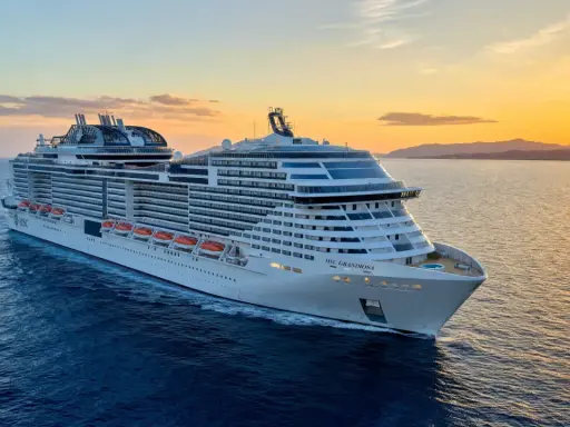 MSC Grandiosa, nave di dimensioni imponenti, solca il mare al tramonto, illuminata dalla luce dorata.