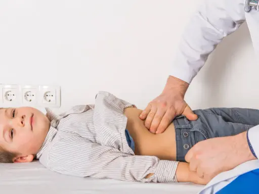 Médico examina el abdomen de un niño con posible gastroenteritis.